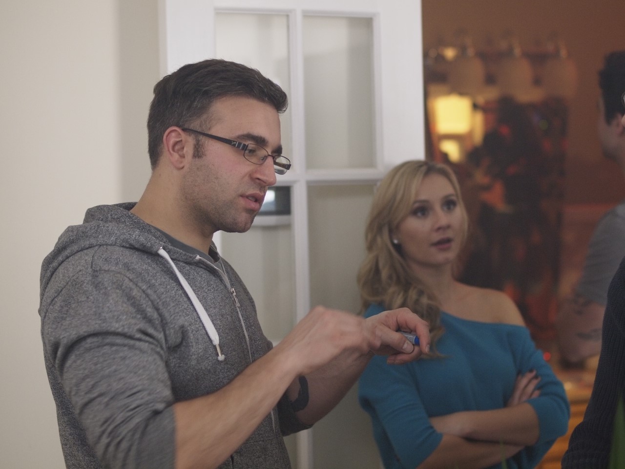 Paul Melluzzo and Julie Dawson engaged in conversation on a film set, one appears thoughtful while the other is surprised.