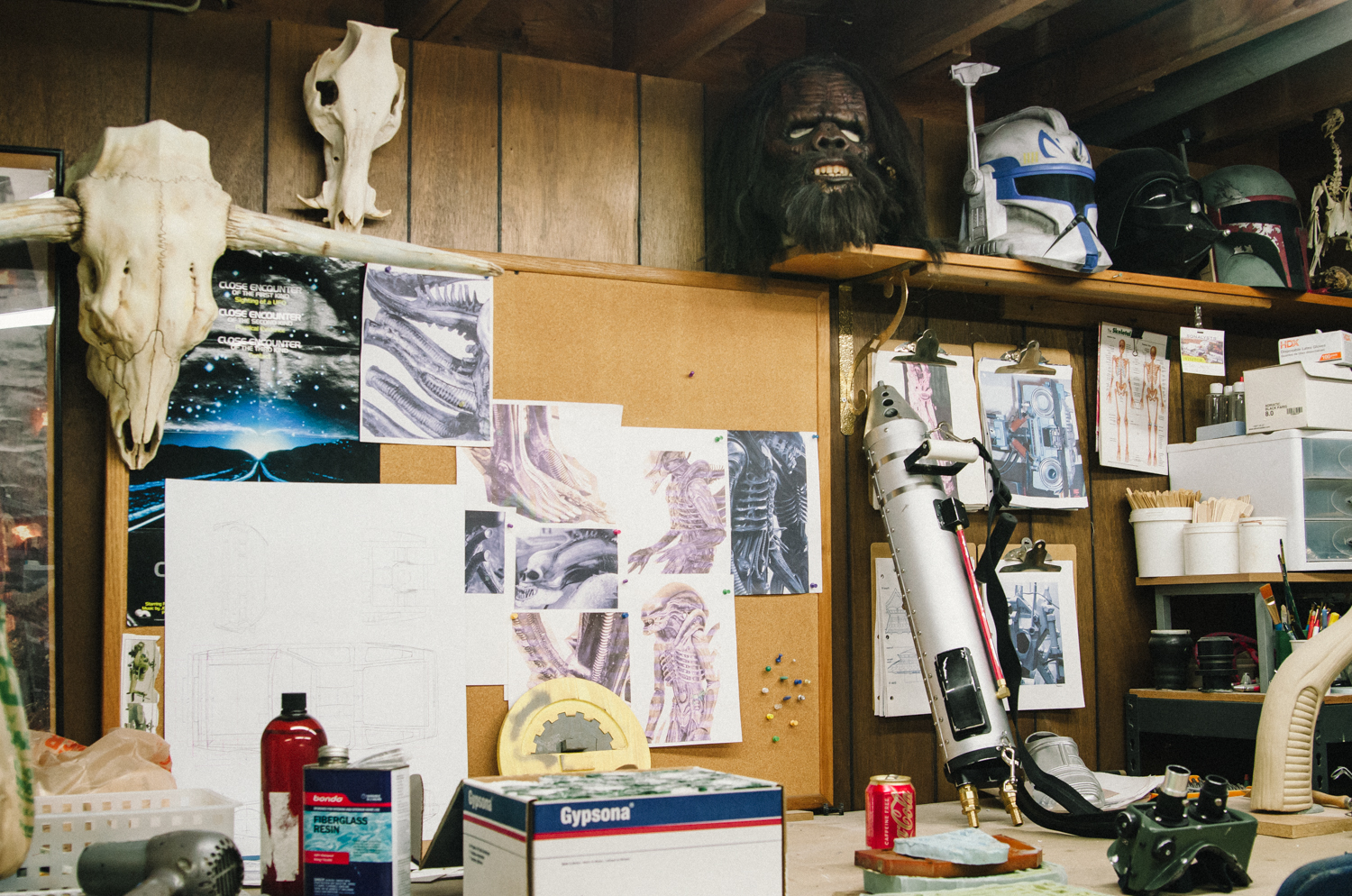 Creative workspace with sketches, masks, and tools on a wooden table showcasing art and design elements.