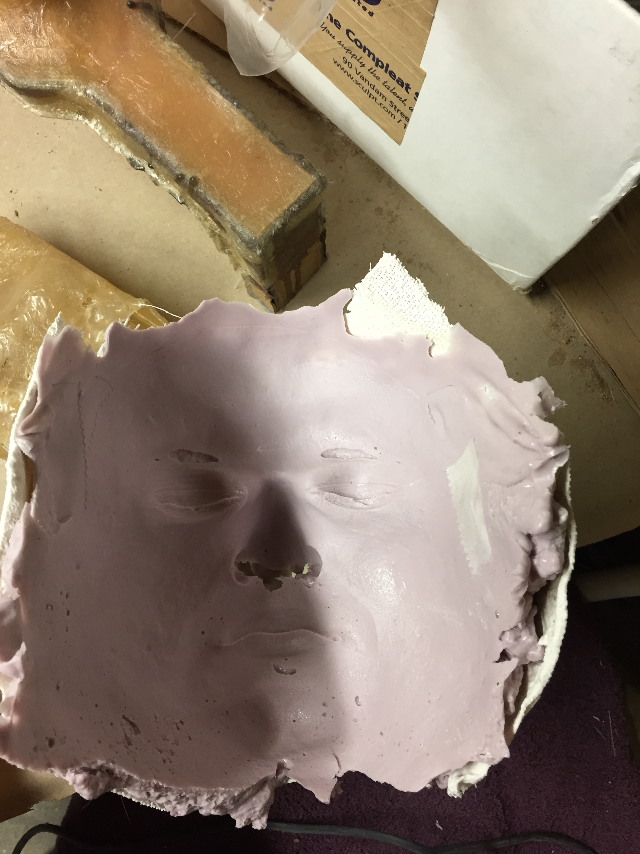 Close-up of a pink face mold on a work surface, showcasing intricate details and surrounding materials.