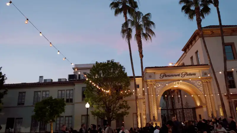 Evening scene at Paramount Pictures with palm trees and string lights outside the iconic entrance.