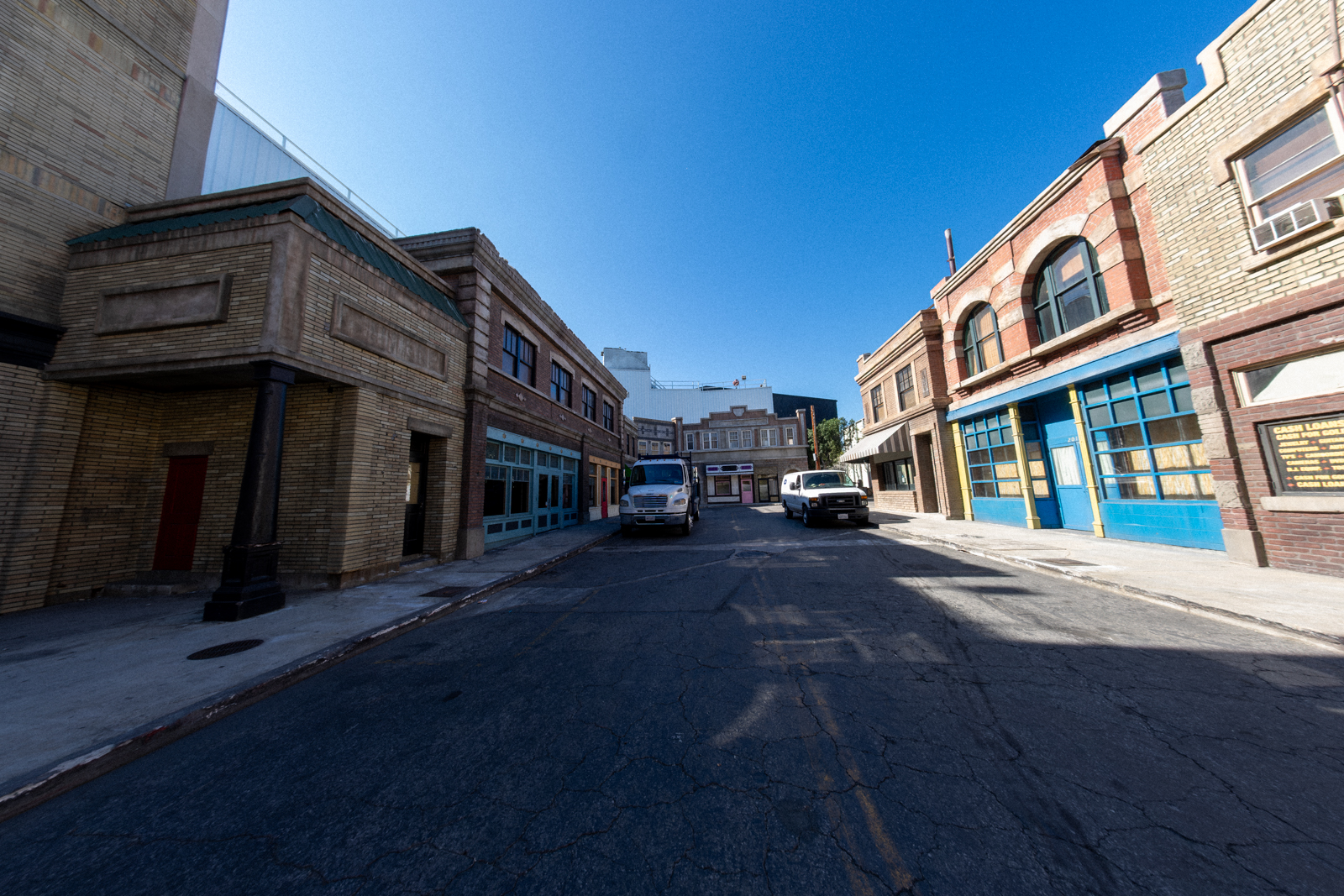 Empty urban street with storefronts and blue skies on a sunny day.