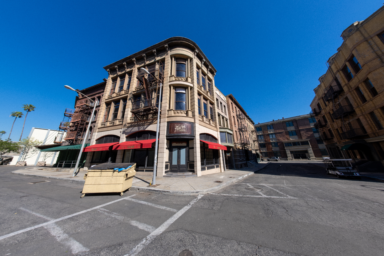 Street view of vintage buildings with red canopies and a yellow dumpster in an urban setting.