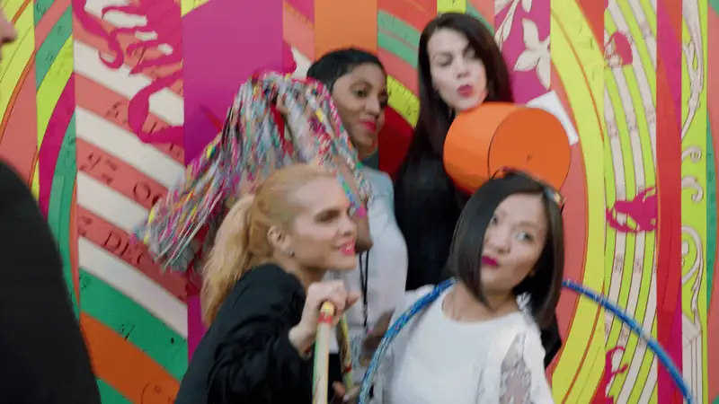 Group of women posing playfully in front of a vibrant, colorful mural