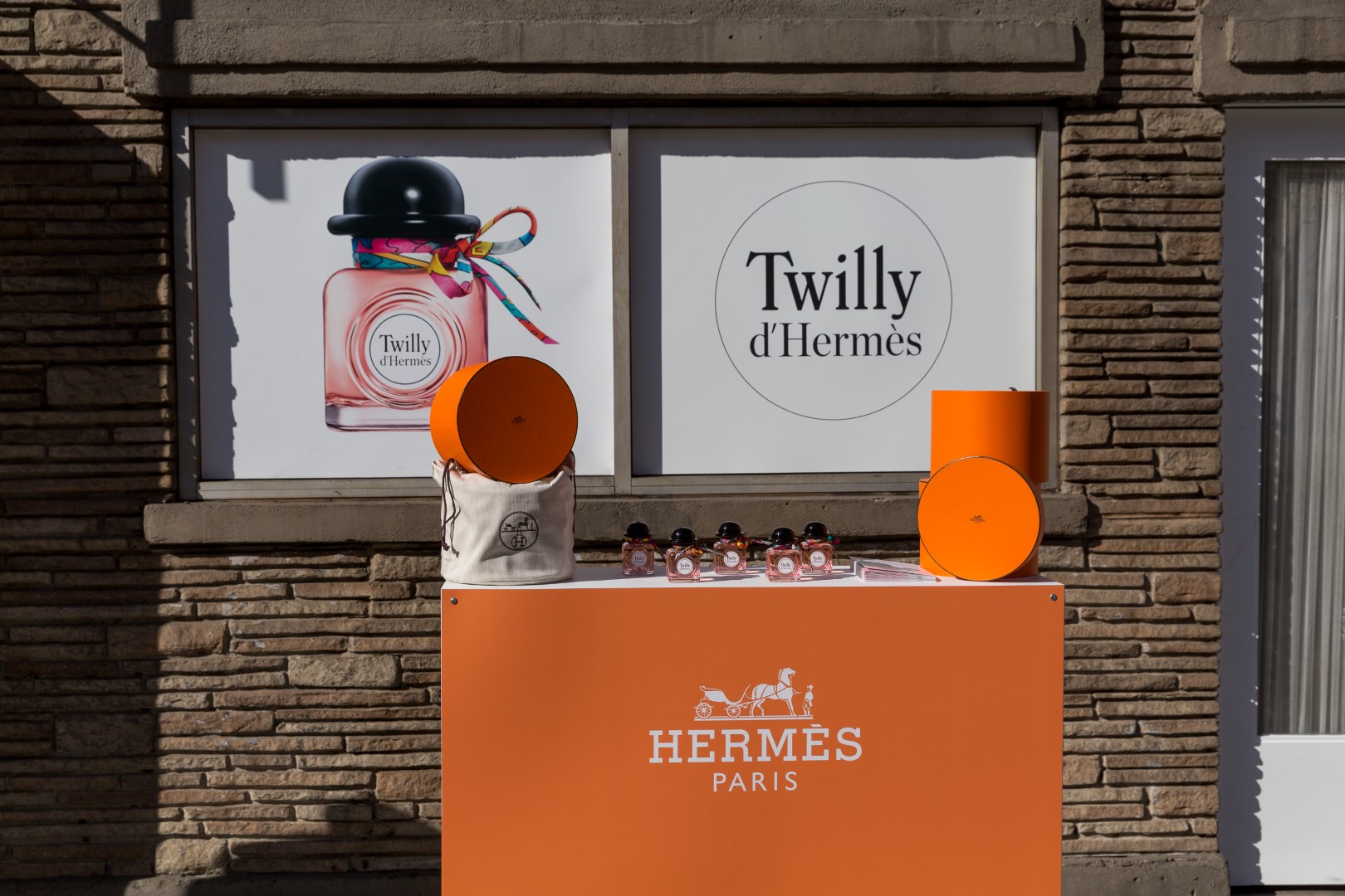 Display of Twilly d'Hermès perfume bottles and packaging outside Hermes popup.