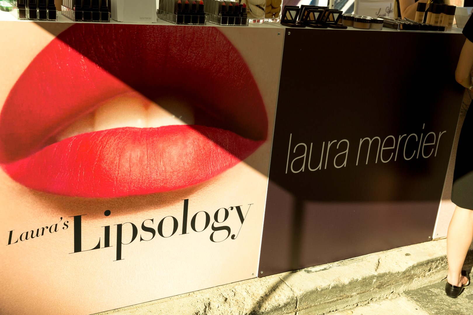 Laura Mercier's Lipsology display featuring bold red lipstick on a lip image.