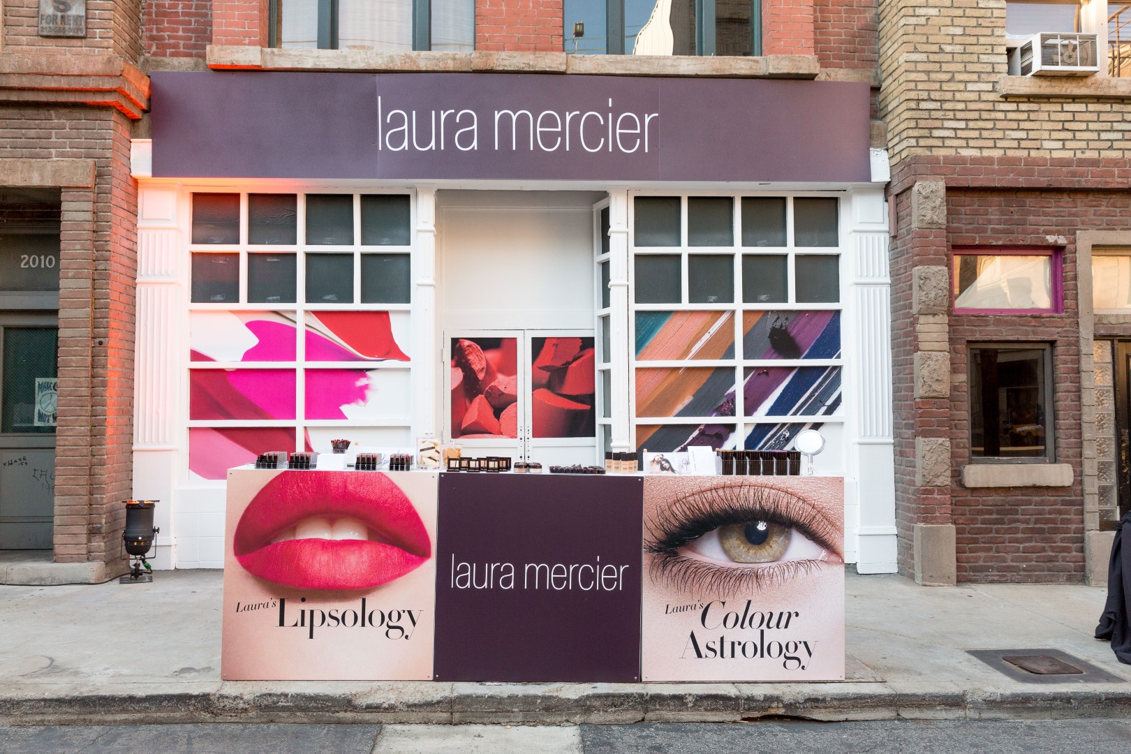 Laura Mercier promotional display featuring Lipsology and Colour Astrology products on a city street.