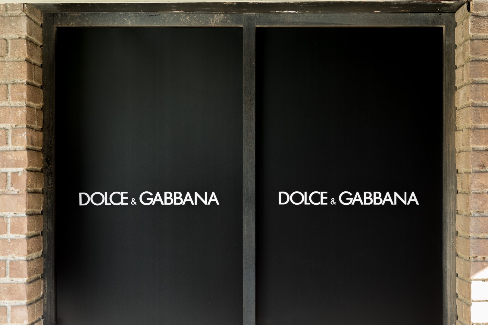 Dolce & Gabbana store entrance with black doors featuring the logo prominently displayed.