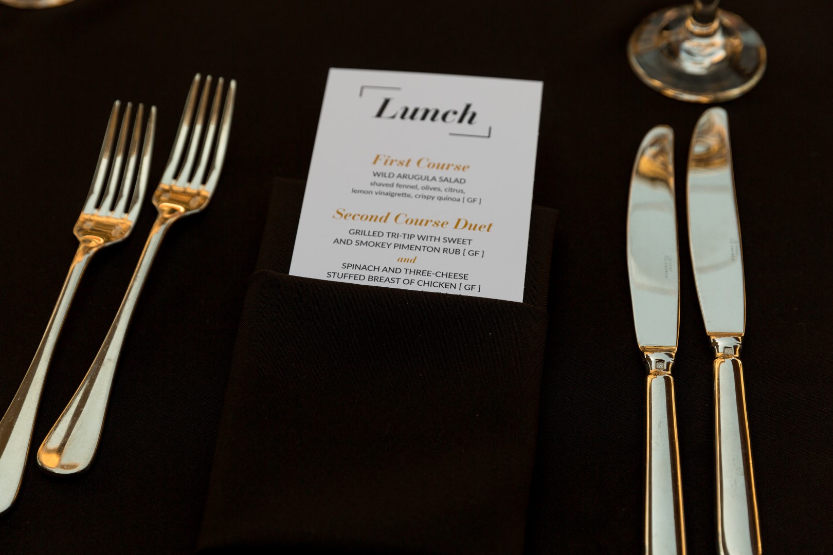 Elegant lunch menu featuring arugula salad and grilled chicken on a black table setting.