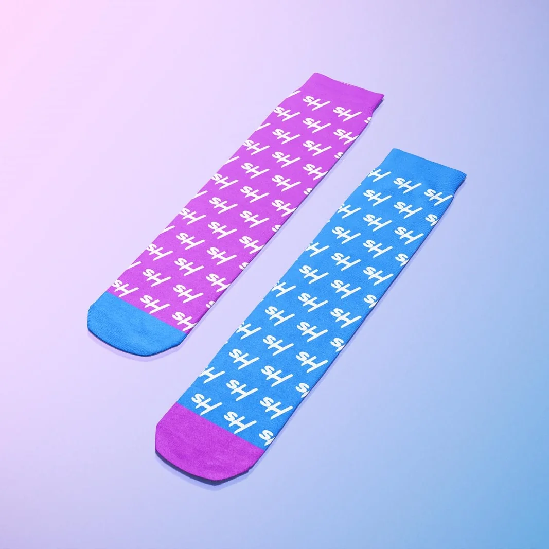 Colorful patterned socks in pink and blue with playful designs on a gradient background.