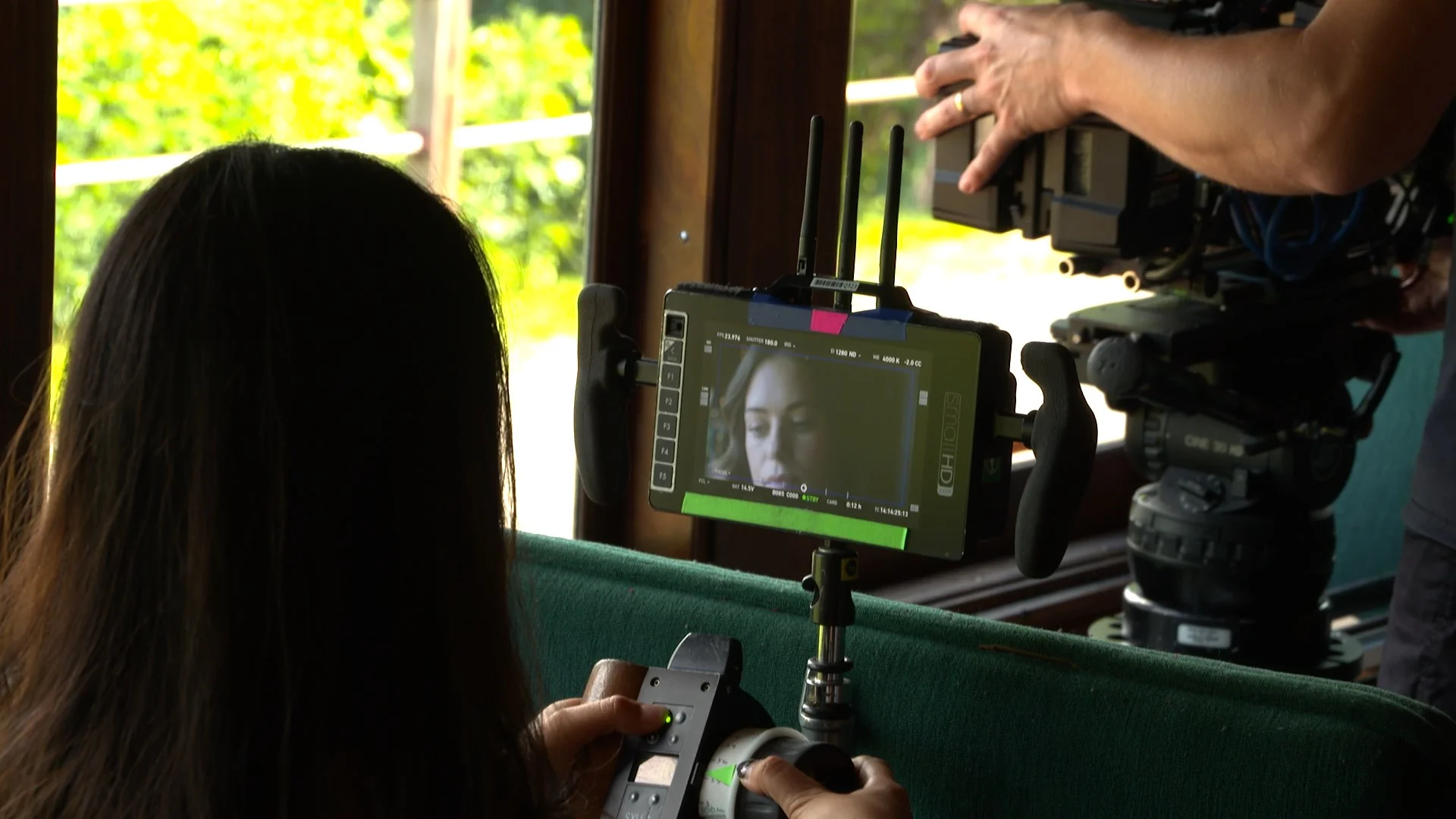 Camera crew filming a scene with monitor showing a close-up of a woman's face.
