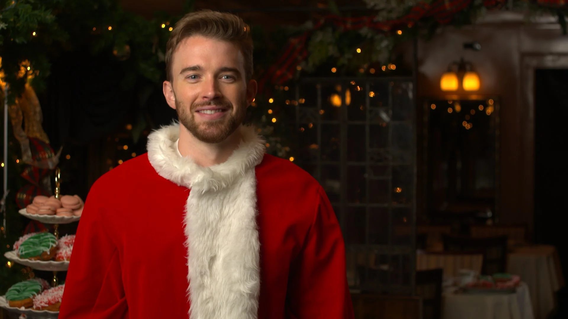 Man in Santa costume smiling in a decorated holiday setting.
