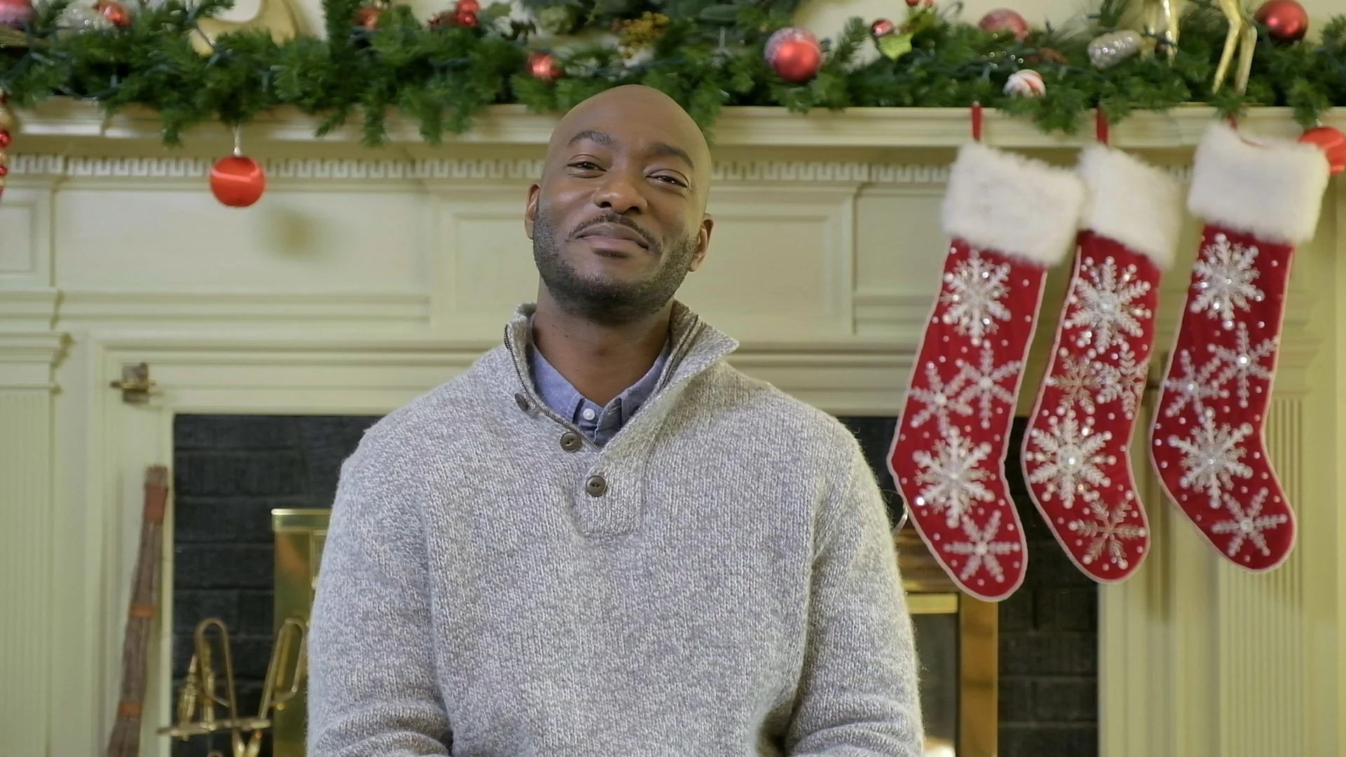 Man smiling in a festive setting with Christmas stockings and holiday decorations