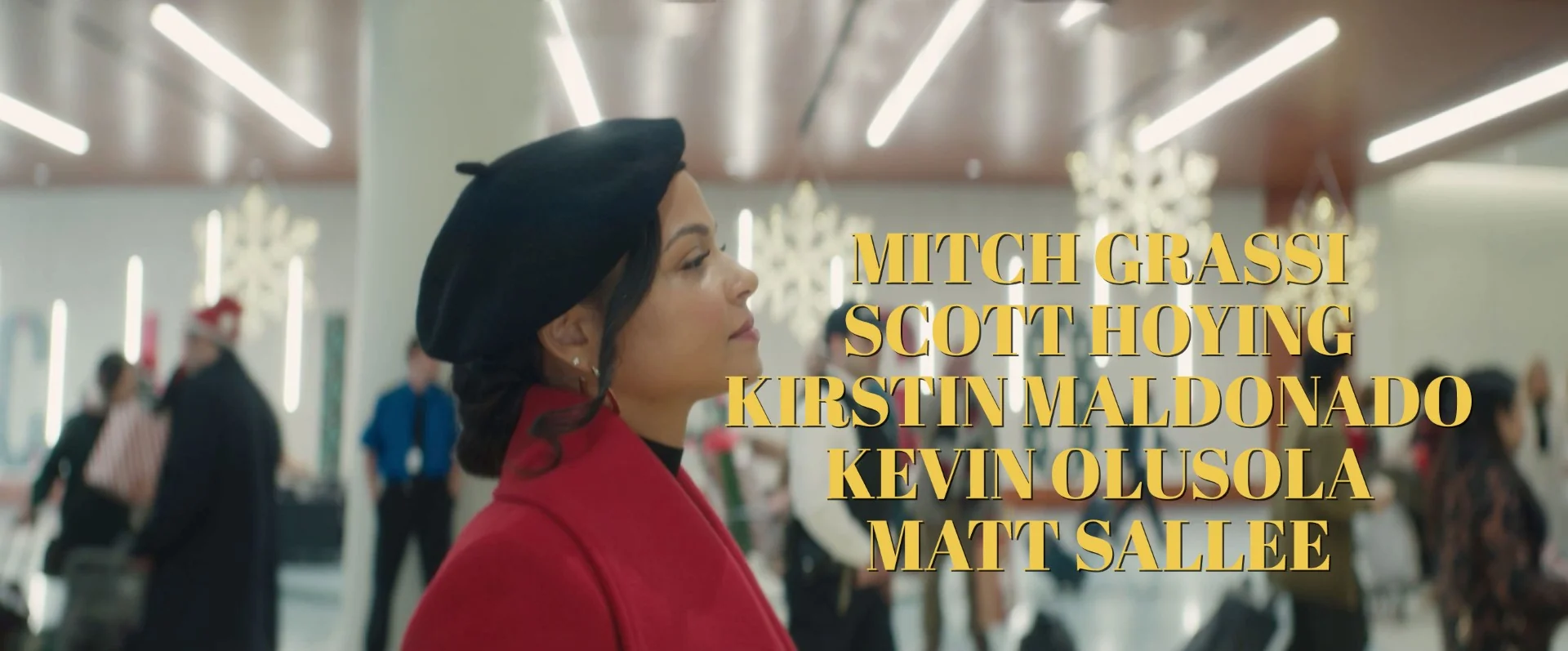 Woman in red coat and black beret with holiday decorations in background.