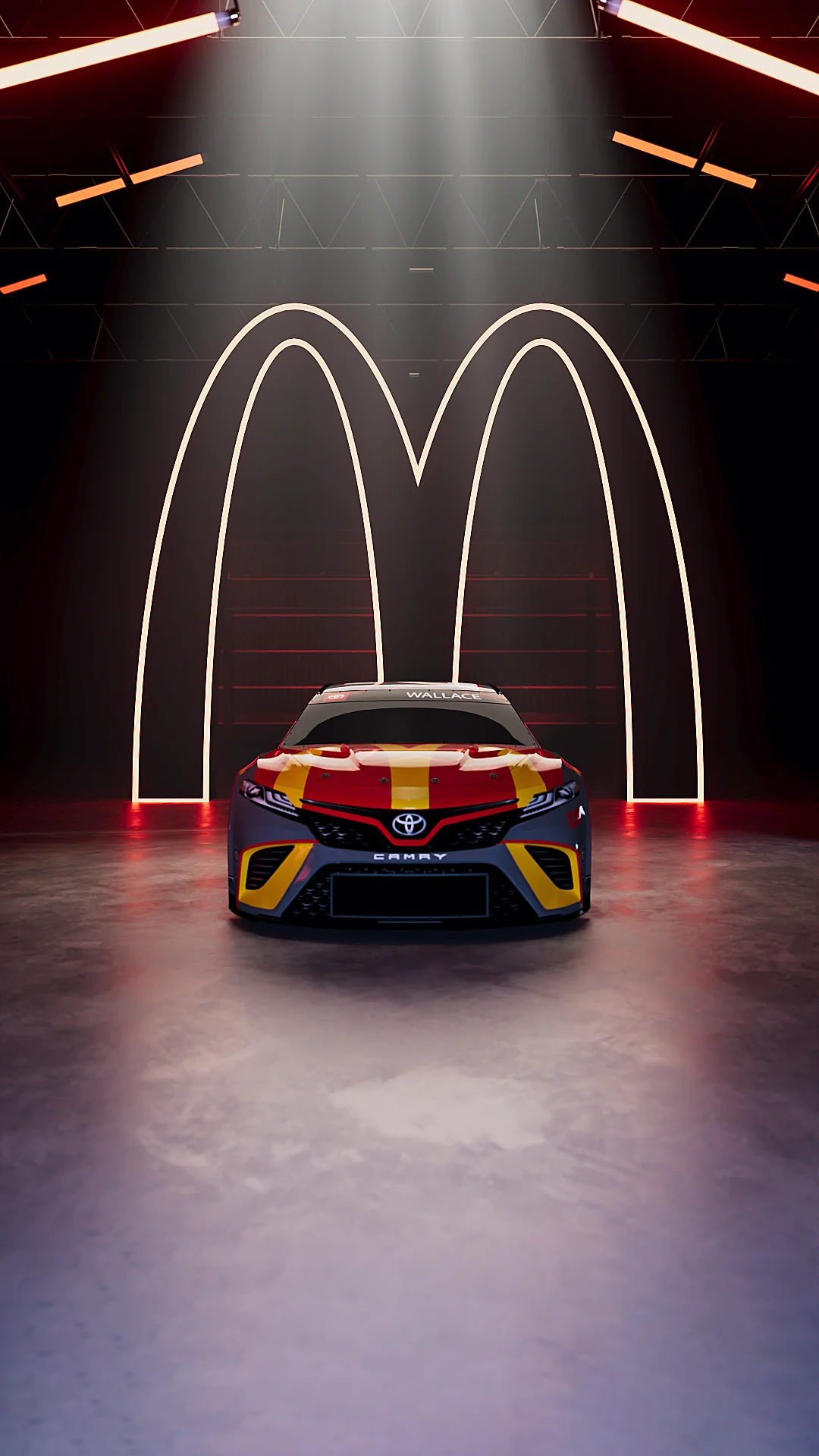 A Toyota Camry race car with a yellow and red design in front of a McDonald's logo.