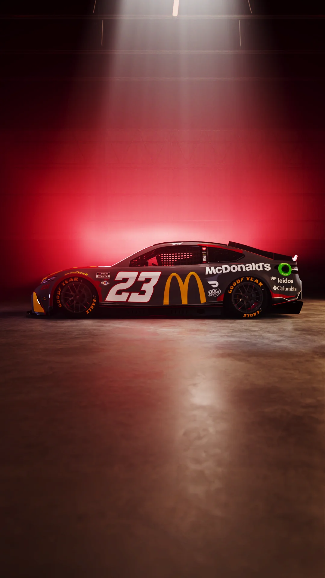 Black race car with McDonald's branding and number 23, illuminated against a red background.