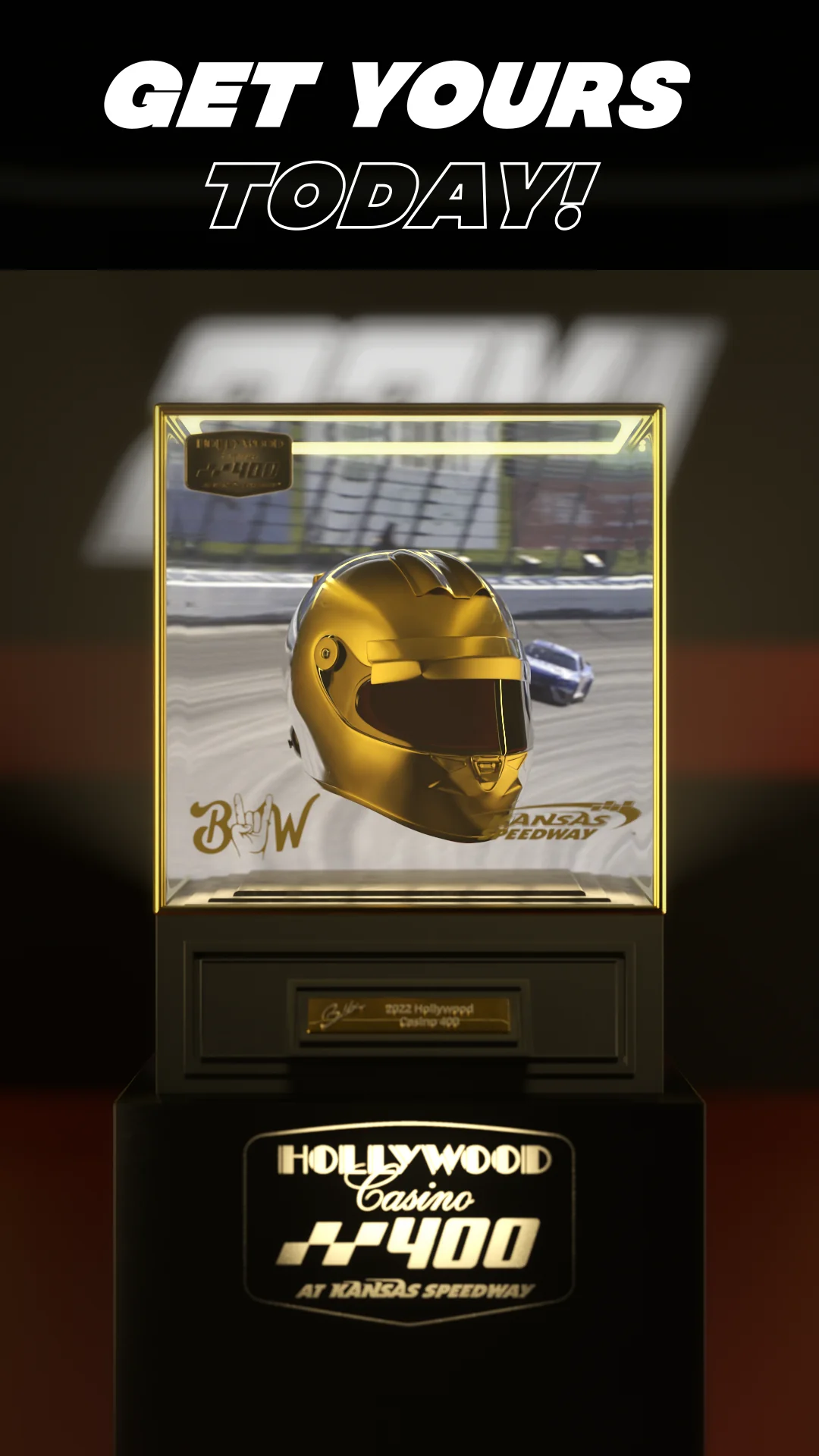Gold racing helmet displayed in a glass case with a Kansas Speedway backdrop.
