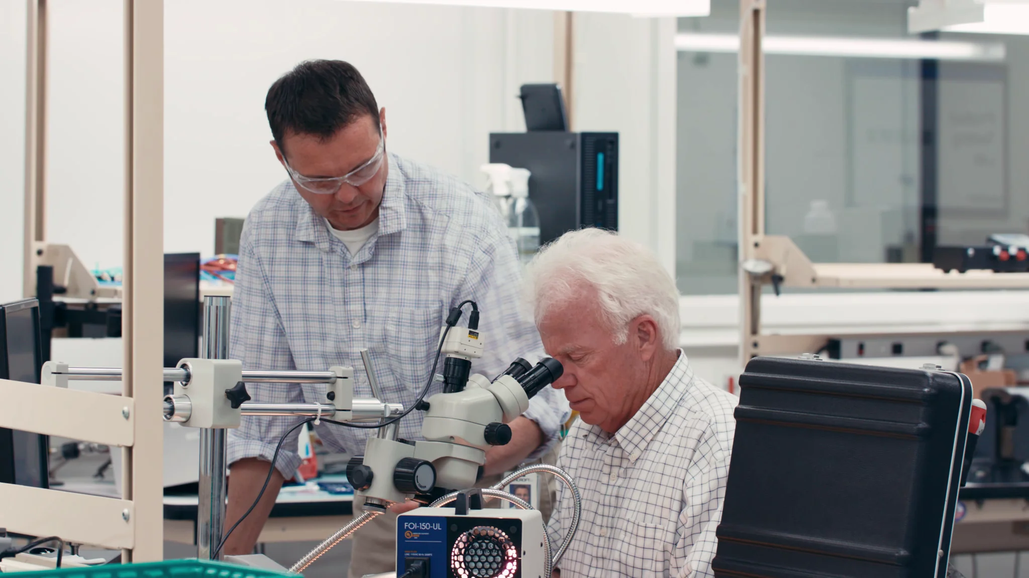 Two men using a microscope in a laboratory setting, focusing on detailed research together.