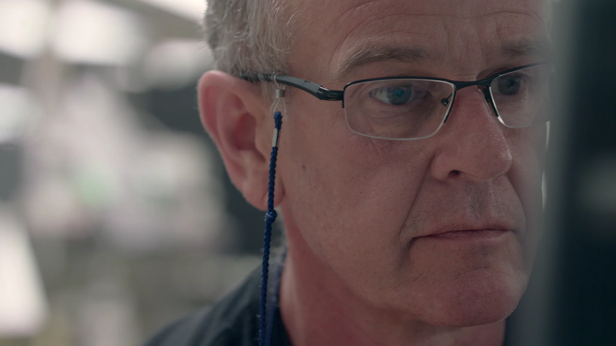 Close-up of a middle-aged man with glasses, concentrating, with a blue strap on his eyewear.