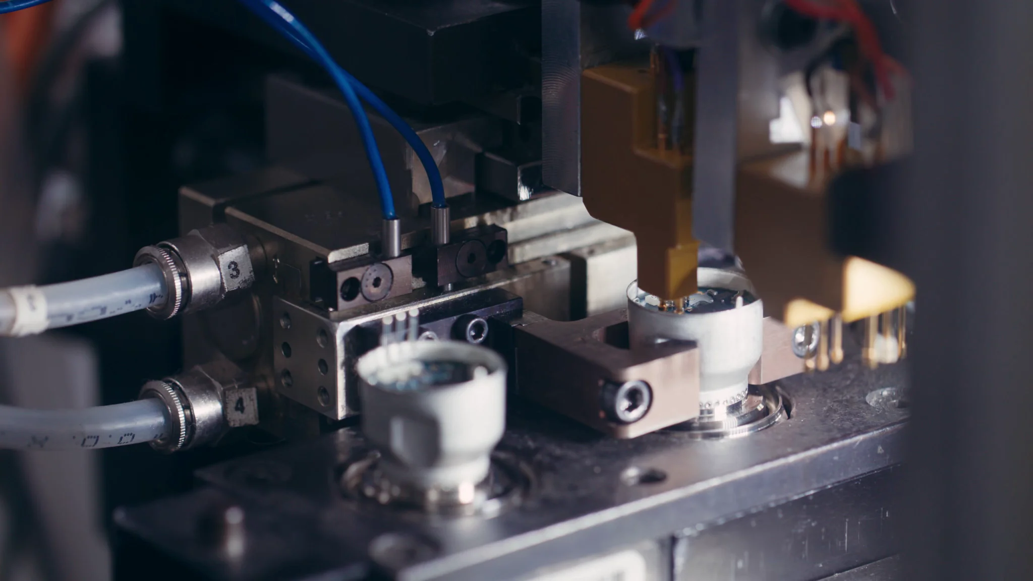 Close-up of an industrial machine component with tubes and precision parts in a manufacturing environment.