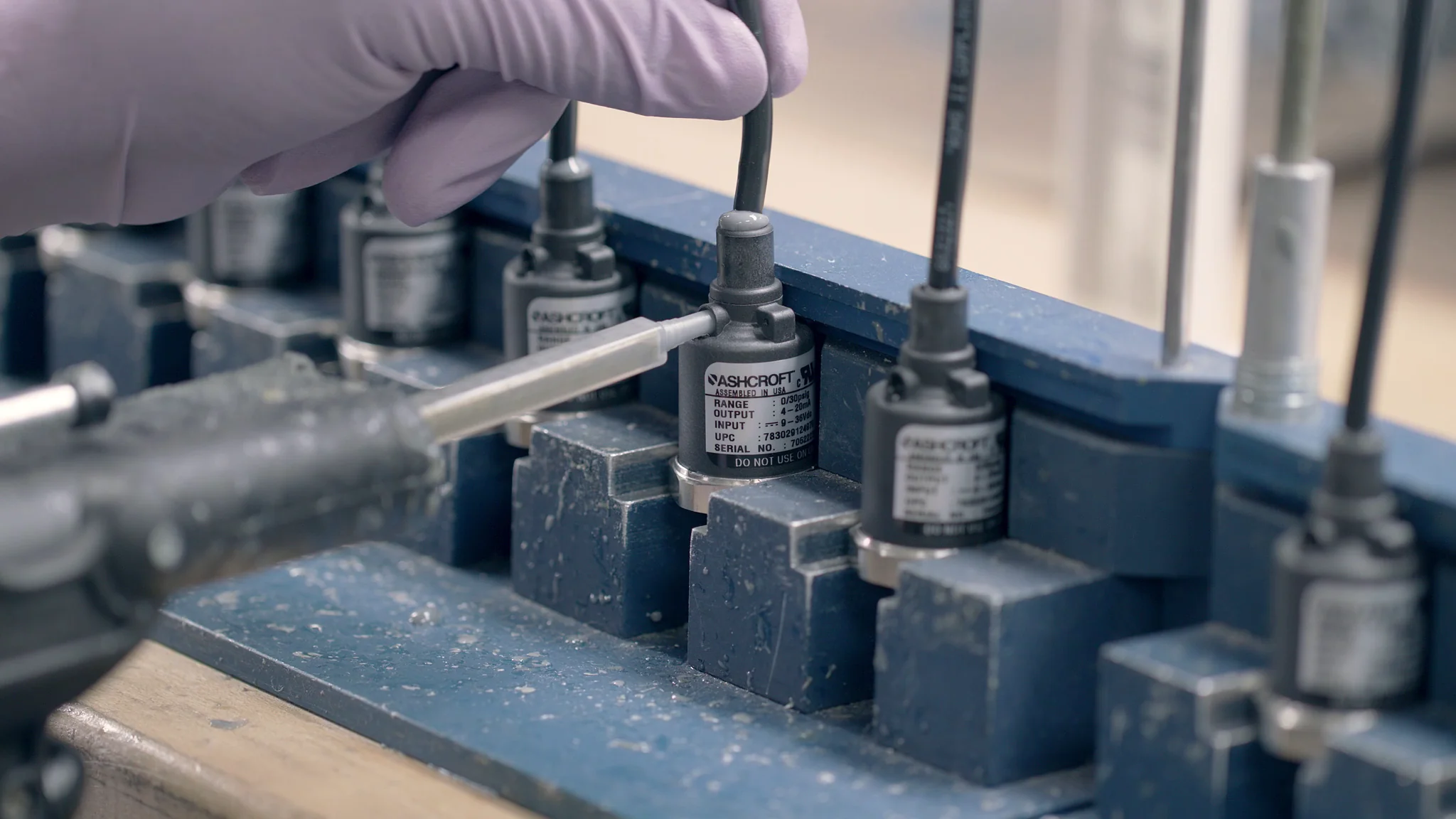 Technician working with Ashcroft sensors and tools in a laboratory setting for precision measurement.