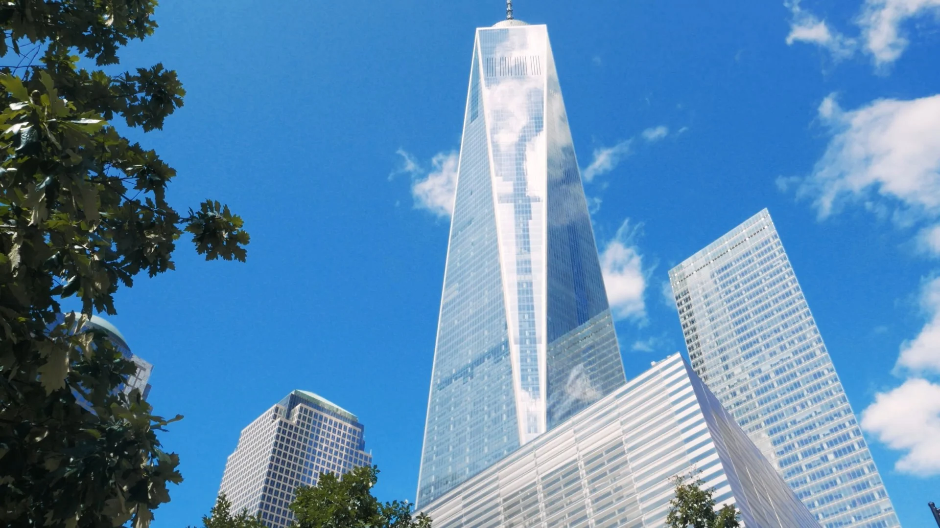 One World Trade Center towering over surrounding buildings under a clear blue sky.