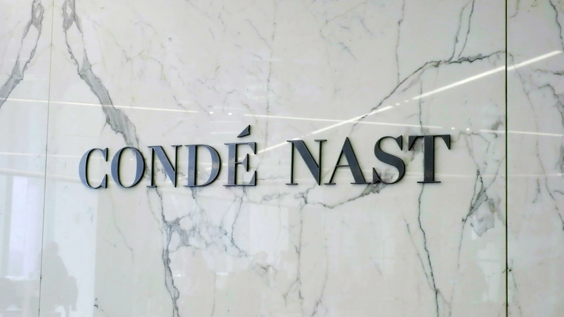 Sign displaying 'Condé Nast' on a marble wall.
