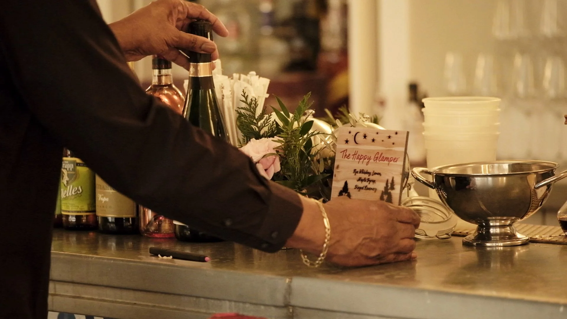 A bartender arranging drinks and decor on a bar counter.