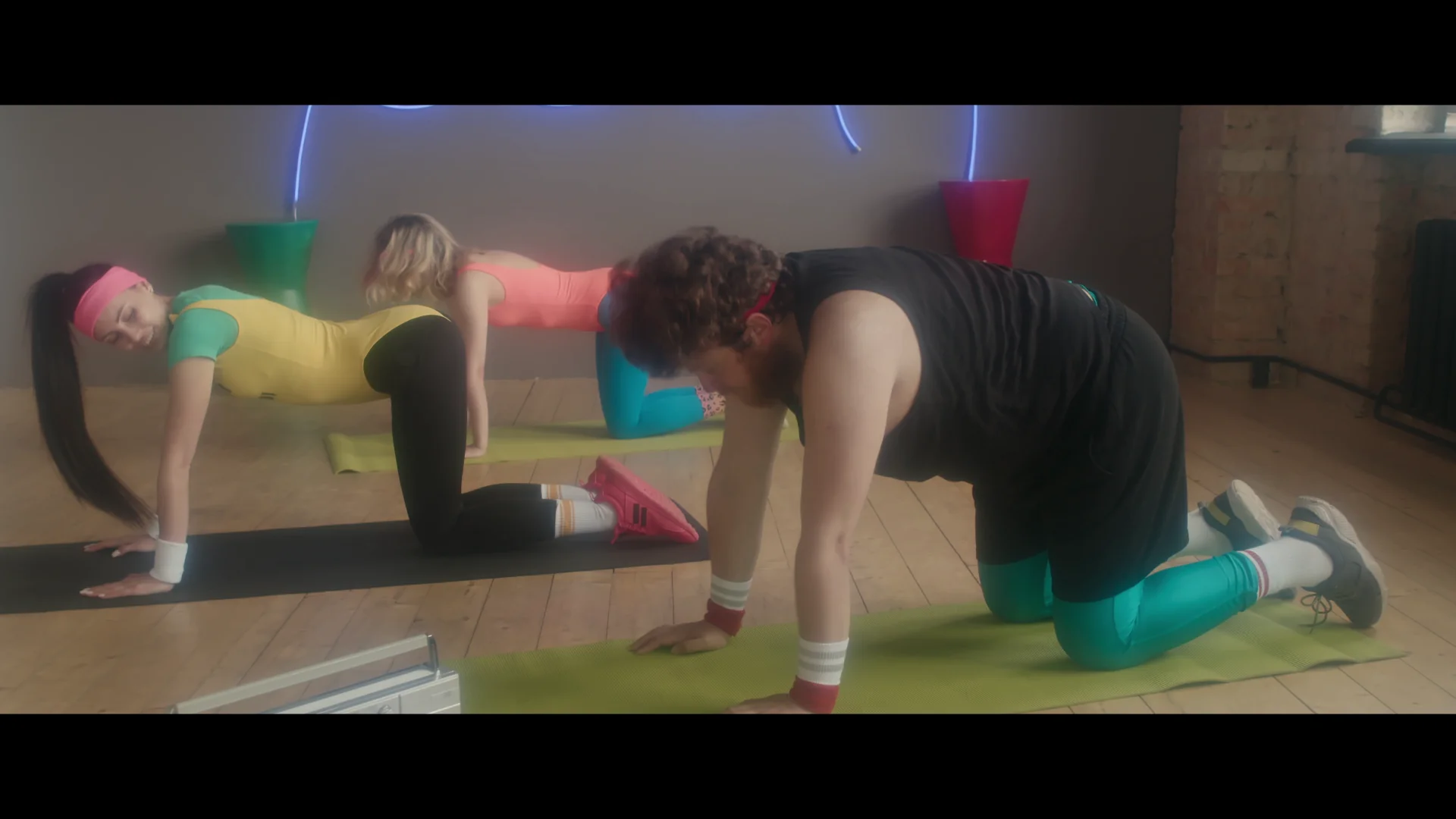 Group workout session with three individuals in vibrant activewear on exercise mats.